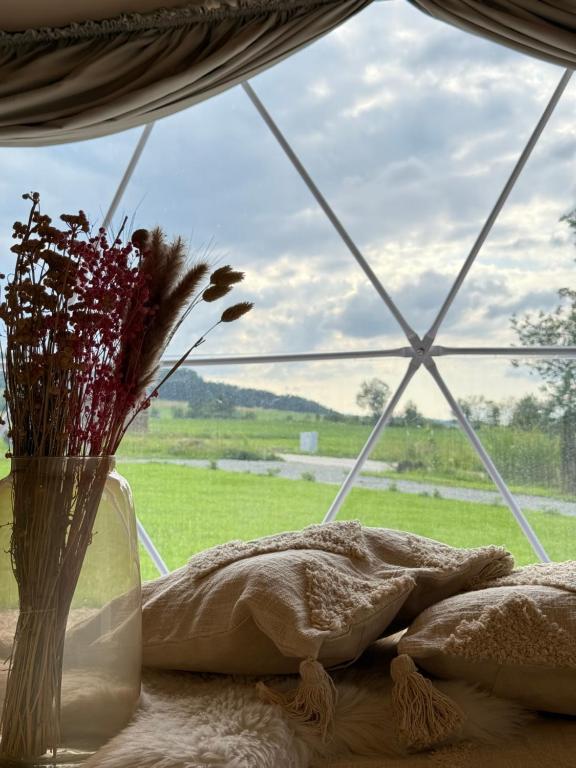 a vase with flowers sitting on a table next to a window at Tatra Glam Krynica Zdrój - Sieć noclegowa Tatra Glamp in Czyrna
