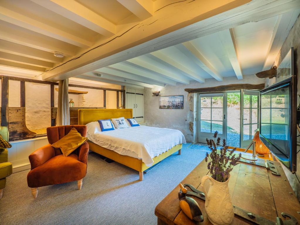 a bedroom with a bed and a couch and a chair at Carmagnac Cowshed in Vaux-Lavalette