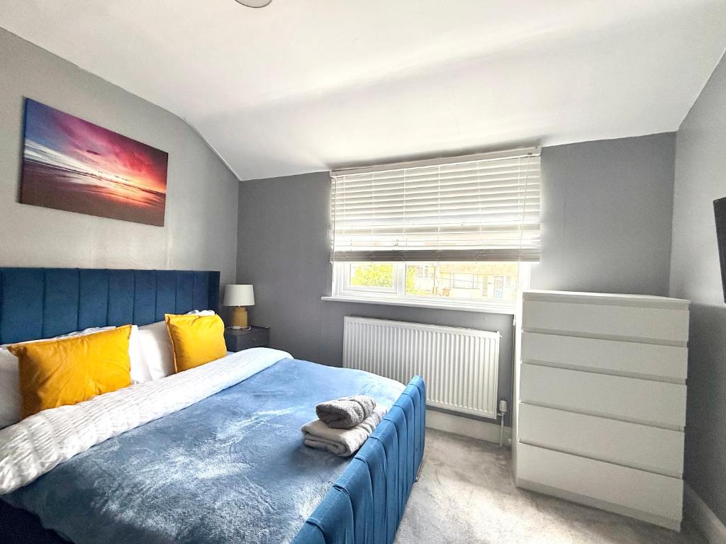 a bedroom with a blue bed and a window at Rochester Cozy 3Bed Home with Free Parking in Strood