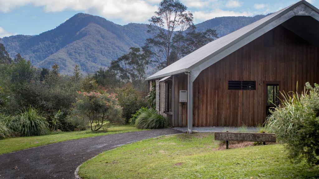 a wooden barn with a road in front of a mountain at Never Never Cabin in Gleniffer