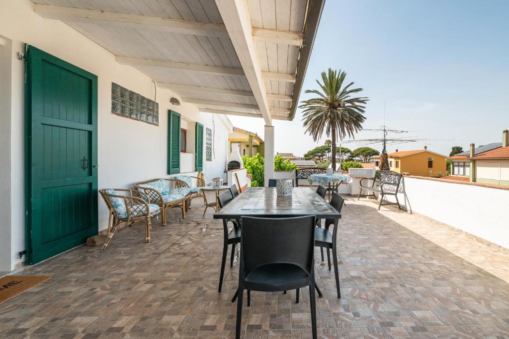a patio with tables and chairs and a green door at Villa D'Oro in La Maddalena