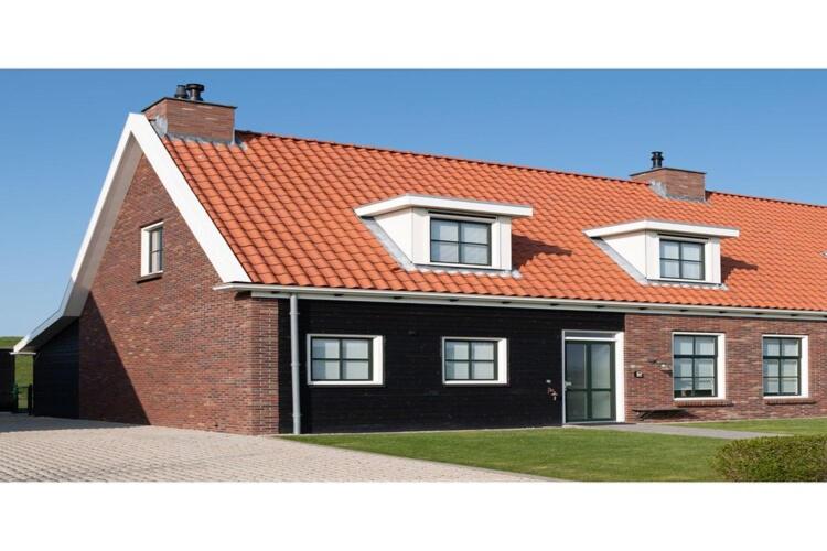 a large brick house with an orange roof at Holiday home with whirlpool and sauna in a quiet area in Zeeland in Colijnsplaat
