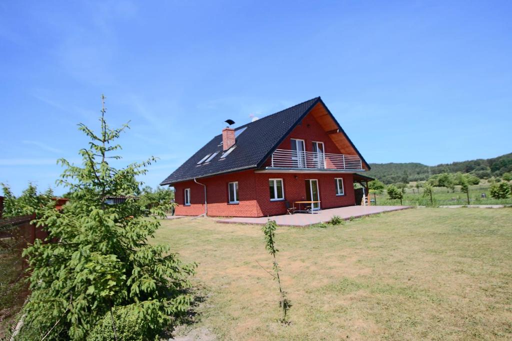 a red barn with a black roof in a field at Willa Turkusowa in Międzyzdroje