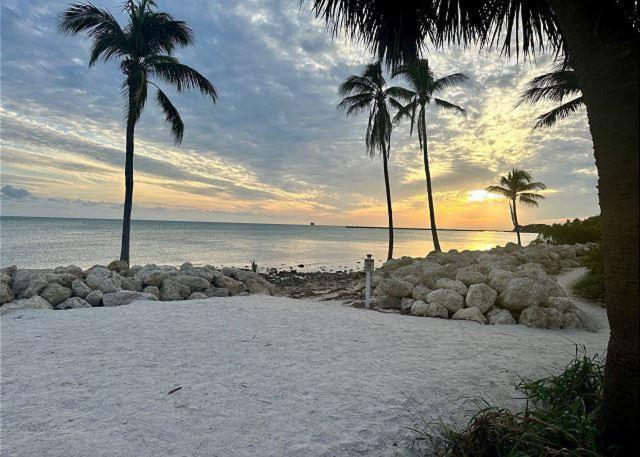 a beach with palm trees and the ocean at sunset at Poolside Breeze Retreat in Key West