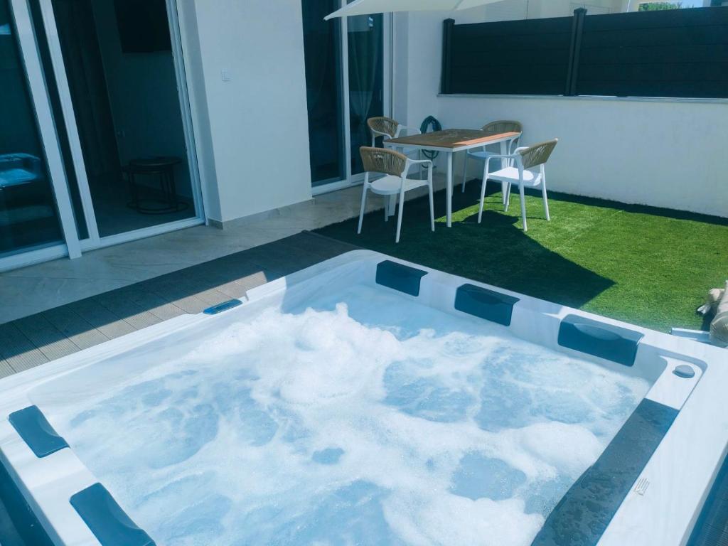 a hot tub in a room with a table and chairs at EriZen Jacuzzi suites in Keramoti
