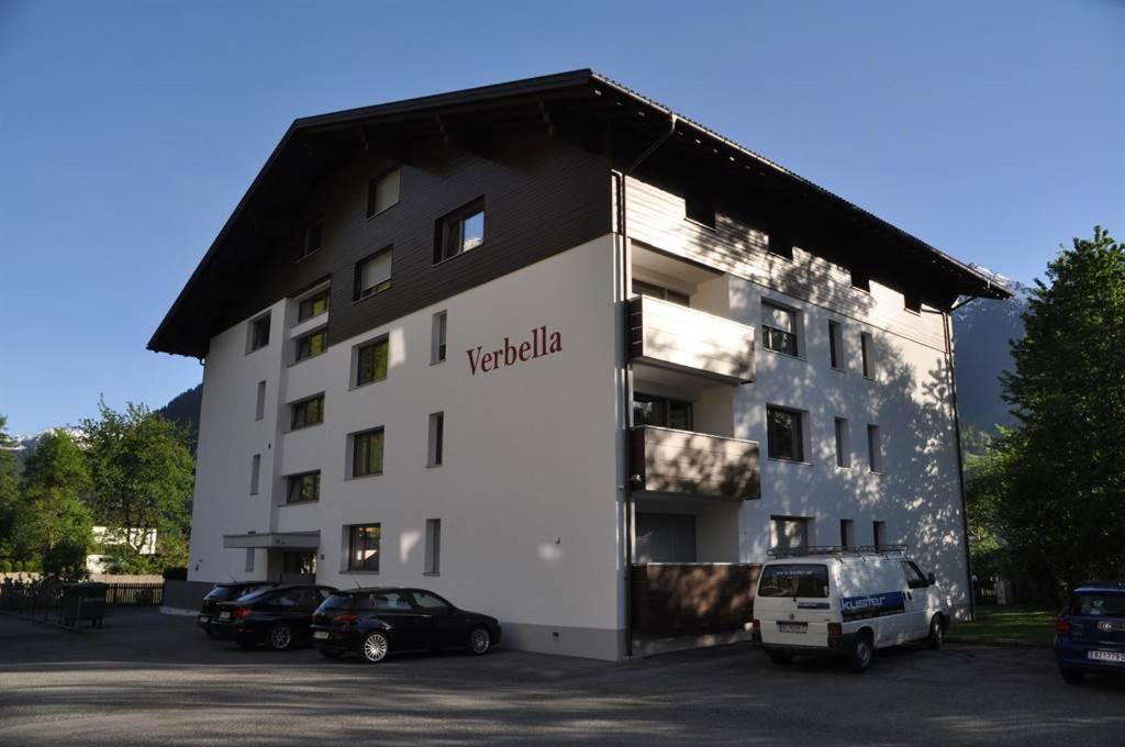 ein großes weißes Gebäude mit auf einem Parkplatz geparkten Autos in der Unterkunft Ferienwohnung Jenny in Schruns-Tschagguns