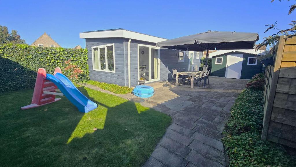 a small house with a slide in the yard at Hello Zeeland - Vakantiewoning Mariekerkseweg 1 in Meliskerke