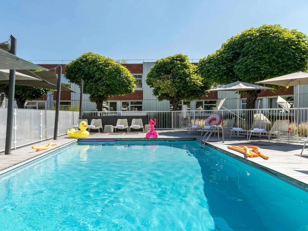 une piscine avec chaises et parasols dans l'établissement Novotel Lyon Bron Meeting & Events, à Bron