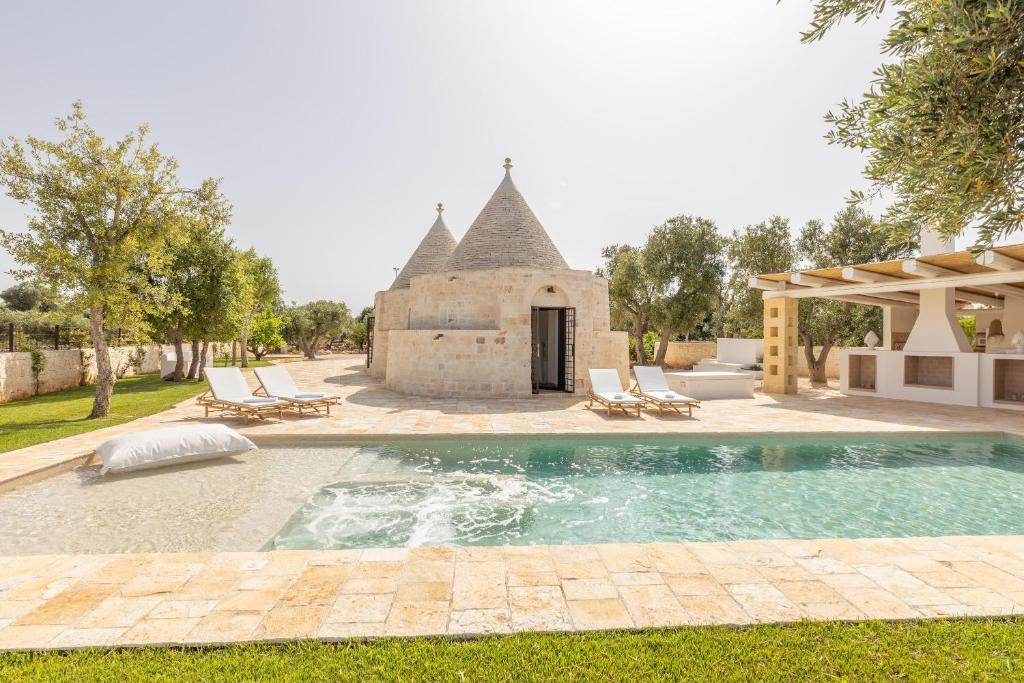 une piscine extérieure avec des chaises et un bâtiment dans l'établissement Villa Trulli del Gelso, à Carovigno