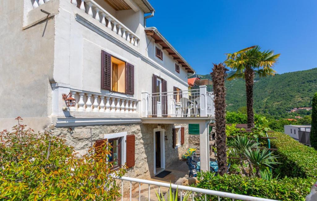 a house with a balcony and a palm tree at Villa Draga by Villas Guide in Mošćenička Draga