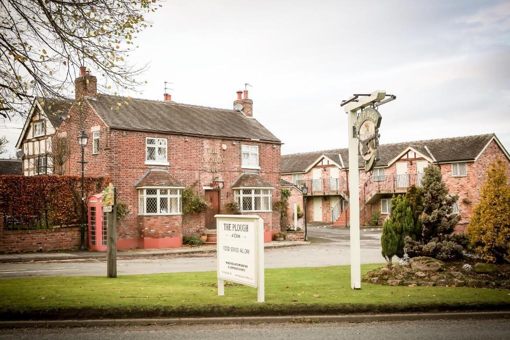 una señal frente a una casa con una torre de reloj en The Plough Inn & Restaurant en Congleton