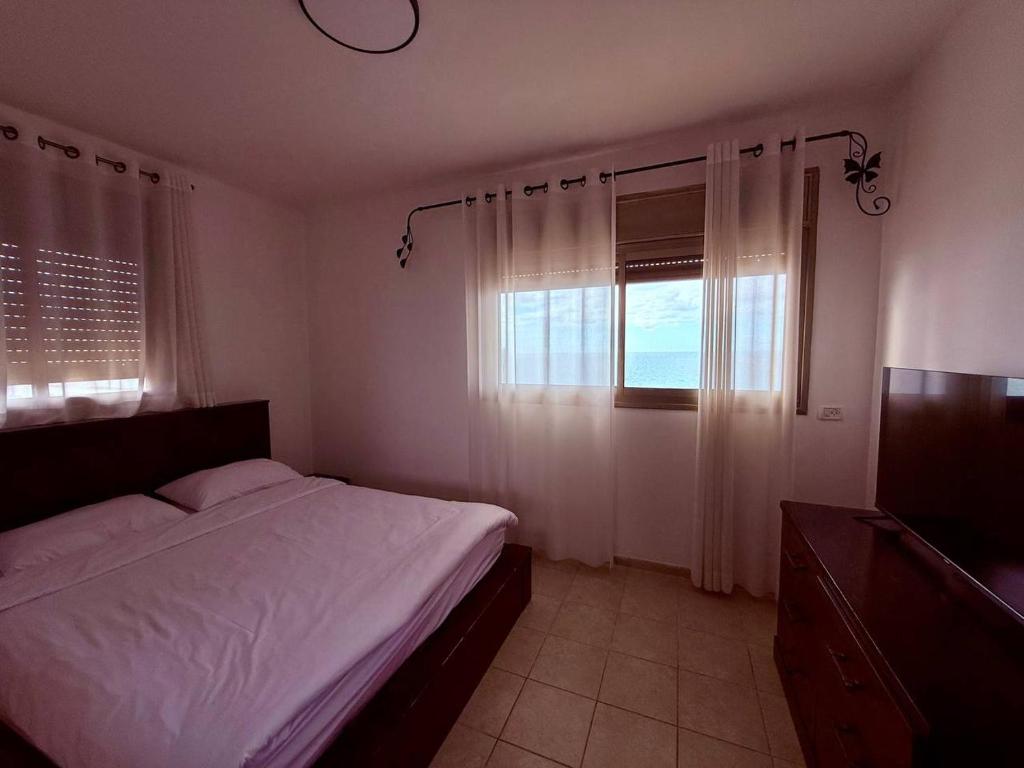un dormitorio con una cama y una ventana en Royal King David Apartment, en Netanya