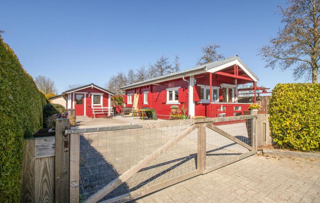 a red house with a fence in front of it at 1 Bedroom Stunning Home In Menaam in Dronrijp