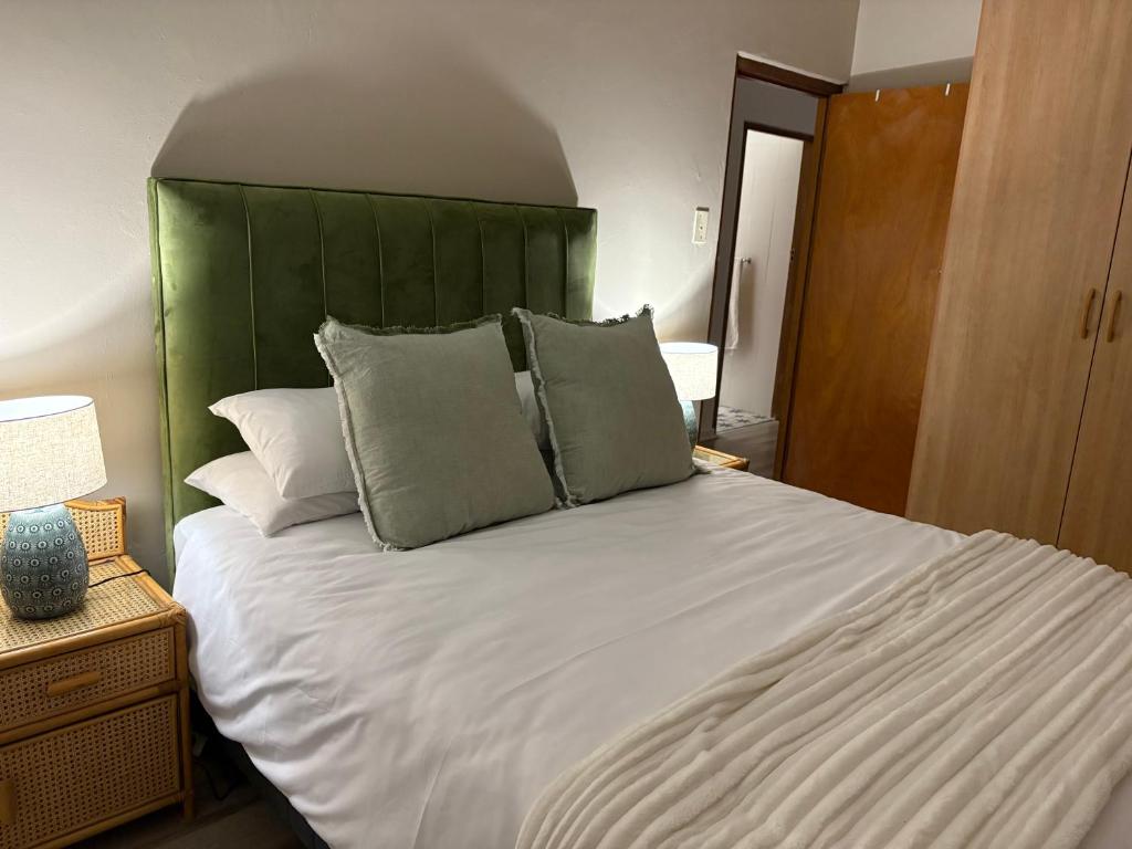 a bedroom with a large white bed with a green headboard at Magic Shot Jeffreys Bay in Jeffreys Bay