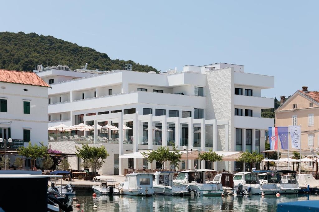 普莱克Hotel Preko Ugljan Island, Curio Collection By Hilton的码头上一座白色的大建筑,有船