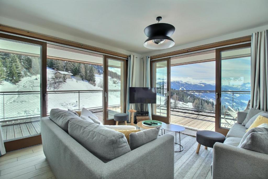 ein Wohnzimmer mit Sofas und einem großen Fenster in der Unterkunft ARC 1600, LE RIDGE, Appartement 10 personnes Vue Montagne - ski aux pieds - Sauna, Hammam, Piscine in Arc 1600