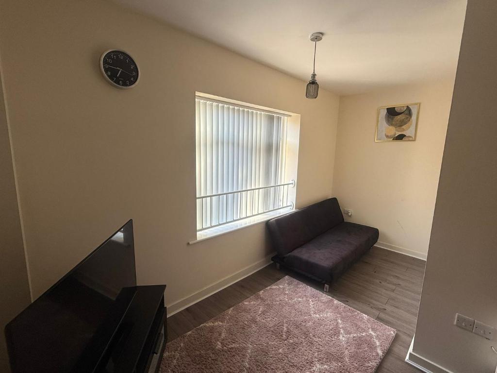 a living room with a couch and a window at Stylish 1-Bed gated Flat with free Parking and steps from Bournemouth Beach in Bournemouth