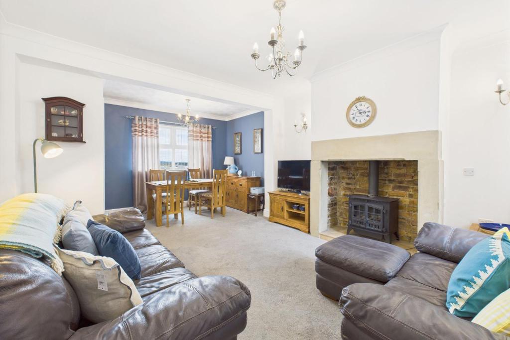 a living room with a leather couch and a fireplace at Host & Stay - Pier View in Amble