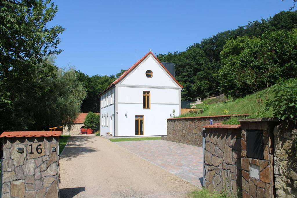 a white house with a stone wall next to a road at Apartment House - Oparno 16 in Velemín