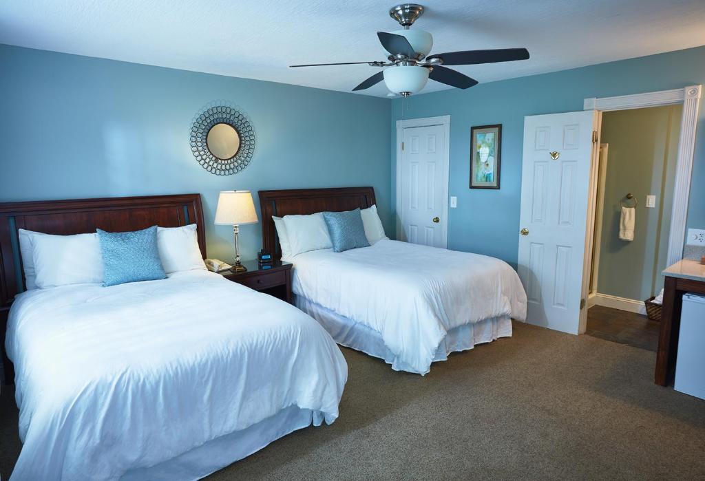 The Mount Vernon Inn في Mount Vernon: غرفة نوم زرقاء بسريرين ومروحة سقف