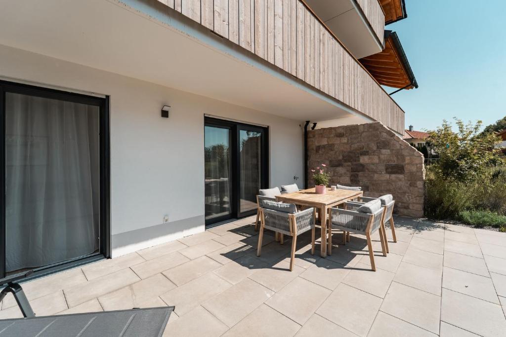 eine Terrasse mit einem Holztisch und Stühlen in der Unterkunft Bay 47° Boutique Apartments am Chiemsee in Übersee