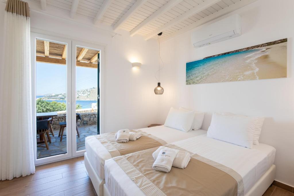 普拉迪斯亚罗斯Seethrough Mykonos Suites的白色卧室,配有带毛巾的床