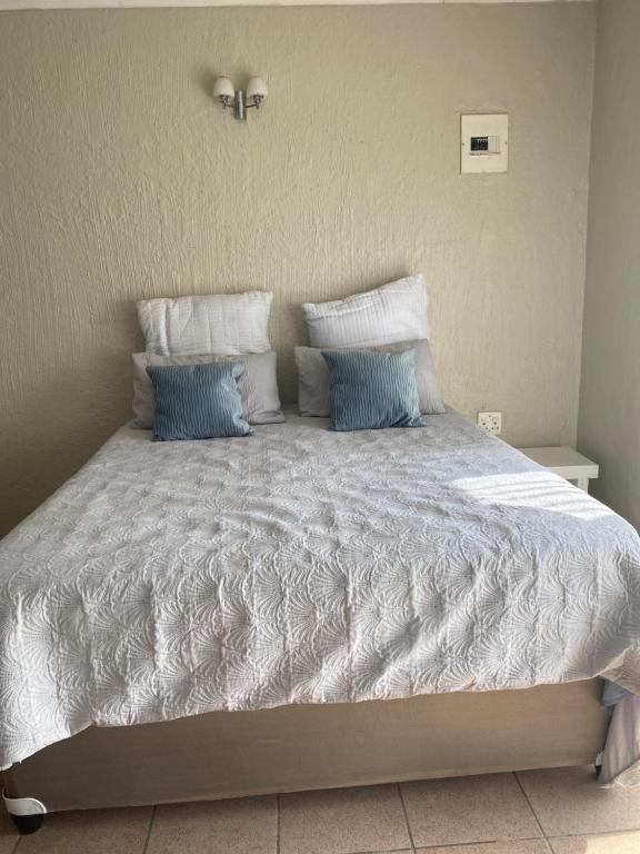 a bed with blue and white pillows on it at Alabaster Rest in Johannesburg