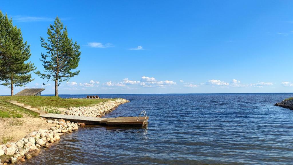 a large body of water with a row of rocks and trees at Villa Dyyni - Oulujärvi Manamansalo in Vaala