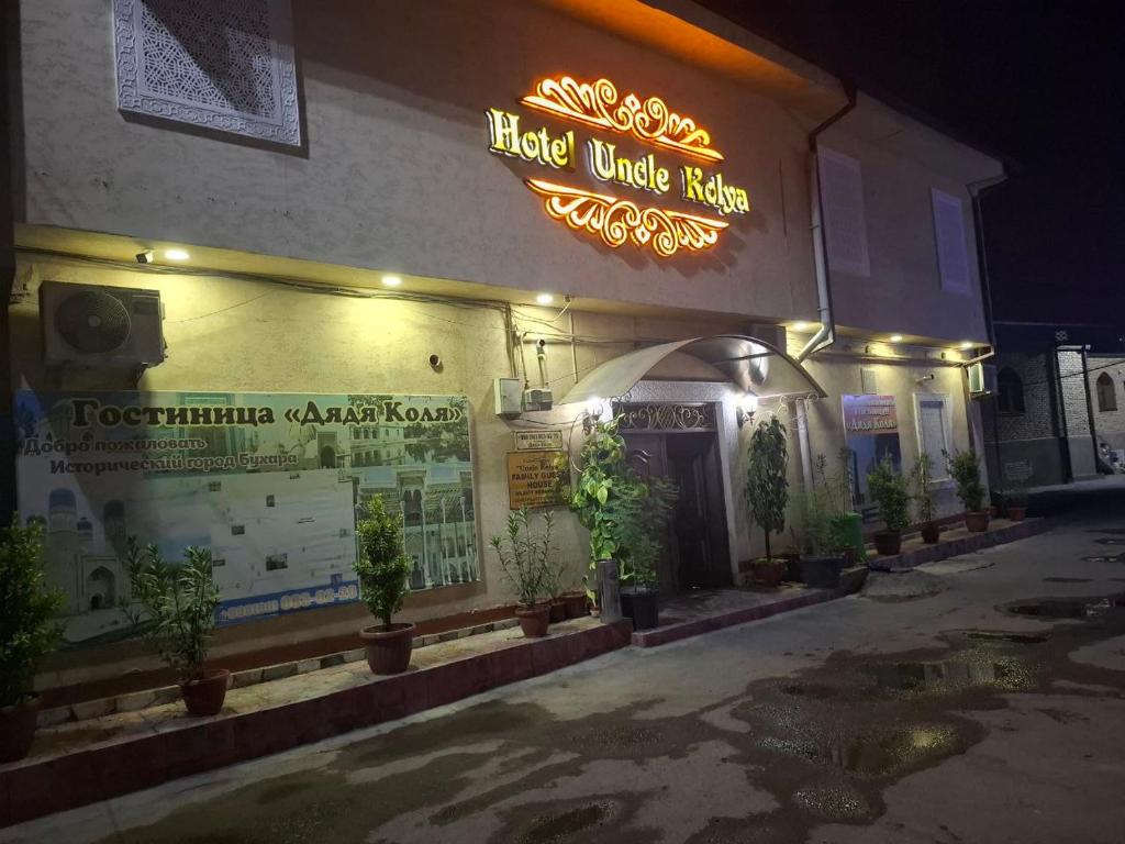 ein Gebäude mit einem Neonschild an der Seite in der Unterkunft Uncle Kolya Hotel str M Azam 39 in Buxoro