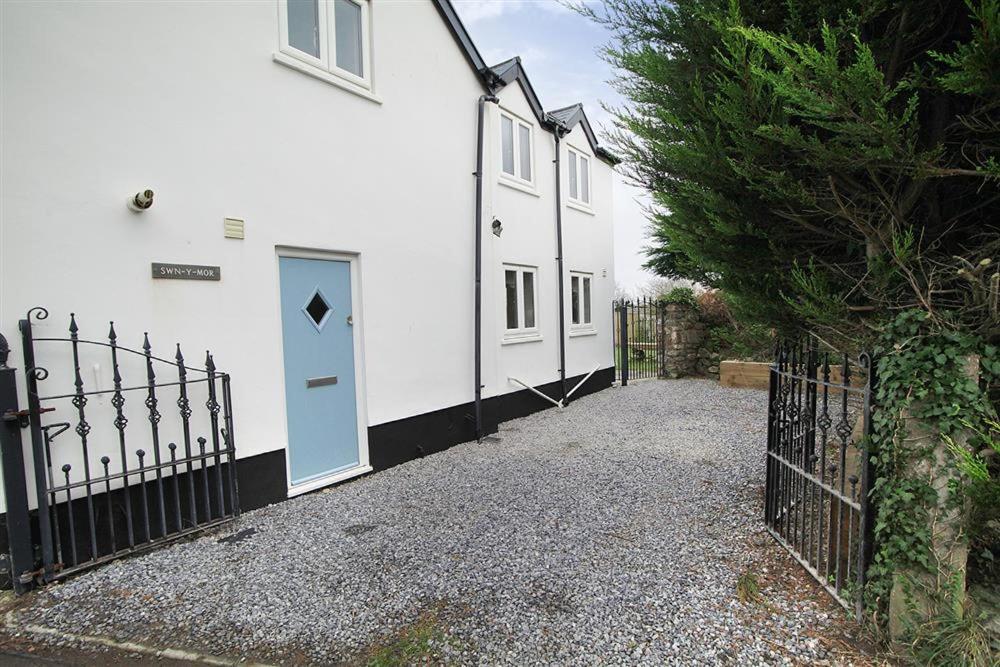 a white house with a blue door and a fence at 4 Bed in Gower oc-hh701 in Port-Eynon
