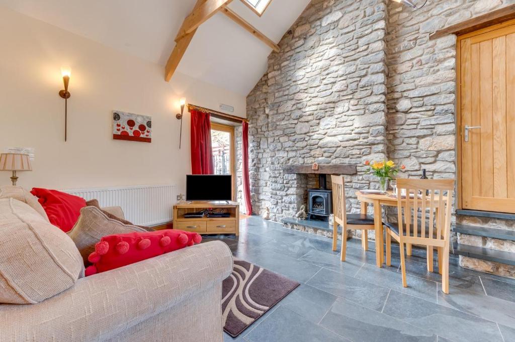 a living room with a couch and a stone wall at The Stable, Llanmadoc in Llanmadoc