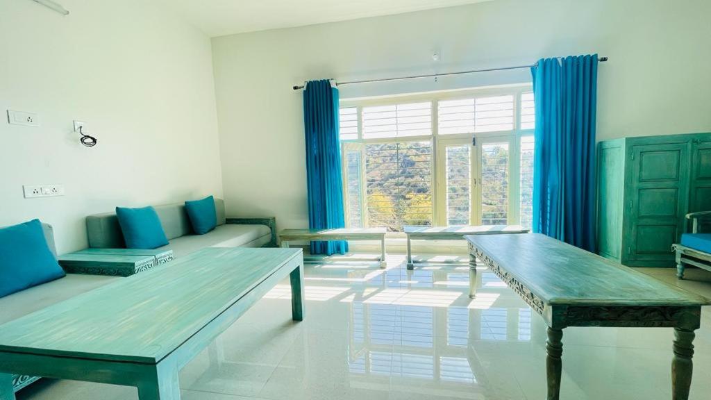 a living room with benches and a large window at Shikhar Bunglow - A Stunning Valley View Bunglow in Mount Abu in Mount Ābu
