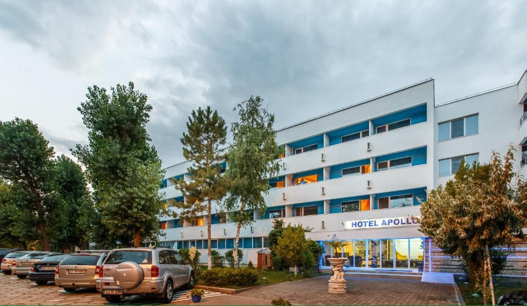 a large white building with cars parked in a parking lot at Hotel Apollo in Mamaia