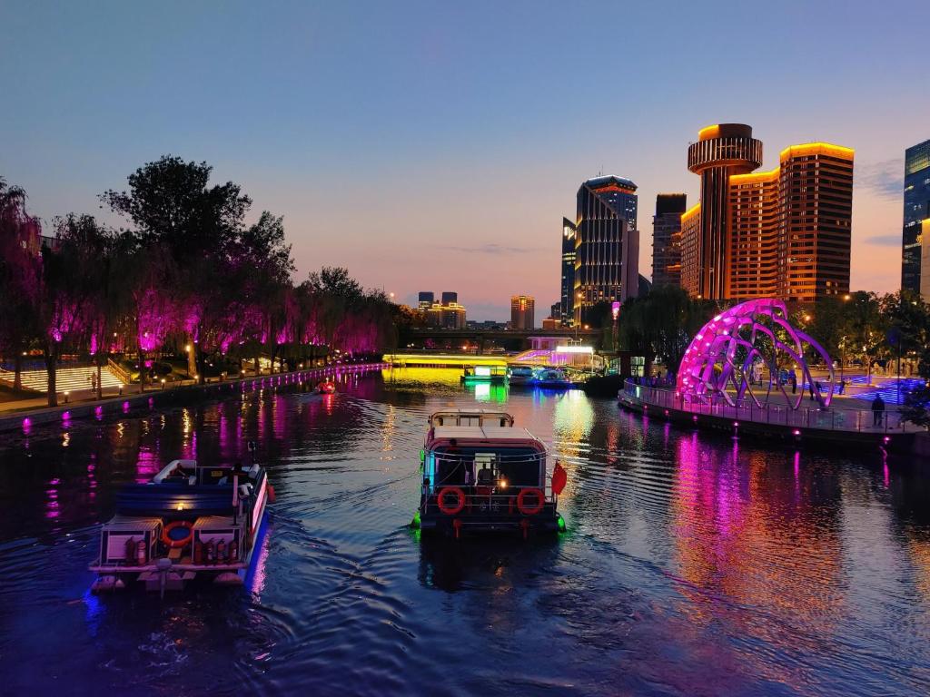 two boats in a river with a city at night at Chinese Culture Boutique Hotel TangFu, Liangma Riverside, Near Sanlitun & Embassy Area, Metro Access, 20min to Wangfujing, Forbidden City & Tian'anmen Square, Airport & the Great Wall Travel Assistance in Beijing