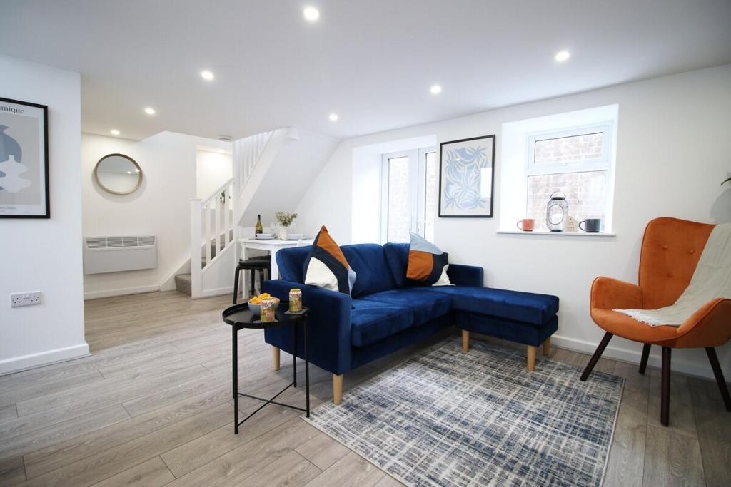 a living room with a blue couch and an orange chair at The White House by Tŷ SA - Zip World & Bike Park in Aberdare