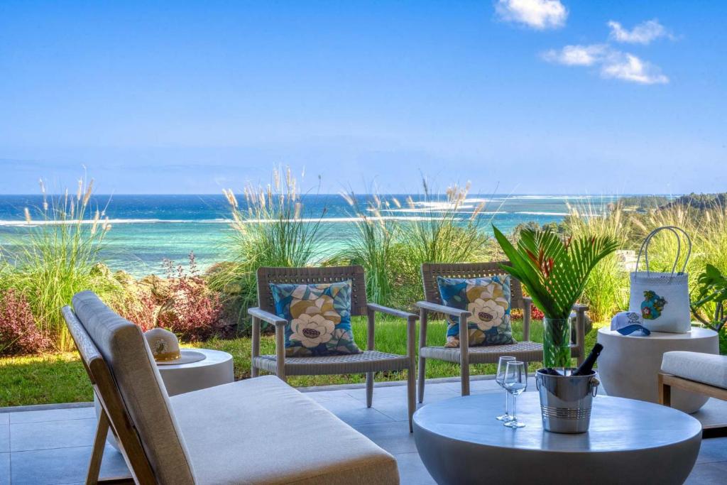 a patio with chairs and a table with a view of the ocean at Domaine d'Anbalaba in Ruisseau Créole