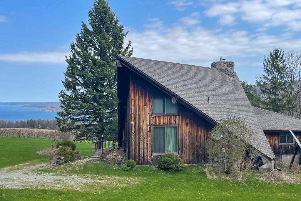 a log cabin with a lake in the background at Near Canandaigua Lake Retro Cabin with Deck and Views in Naples