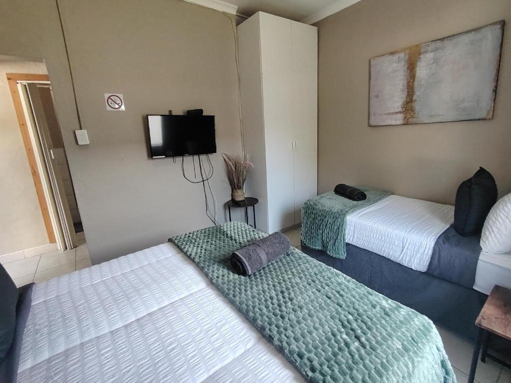 ein Zimmer mit zwei Betten und einem Flachbildfernseher in der Unterkunft Cornelia Place in Sunridge Park