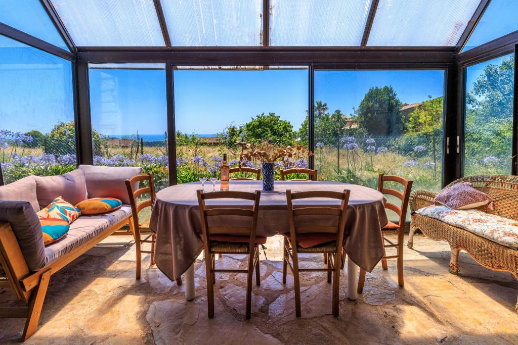 a glass conservatory with a table and chairs and a couch at Maison Canorgues in Tourrettes-sur-Loup