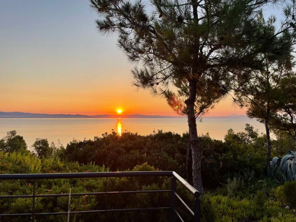 a sunset over the water with a lighthouse in the distance at THEA MARE villa in Nea Potidaea