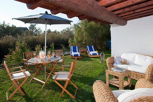 a patio with a table and chairs and an umbrella at Mangio Fango Hotel et Spa in Saintes-Maries-de-la-Mer
