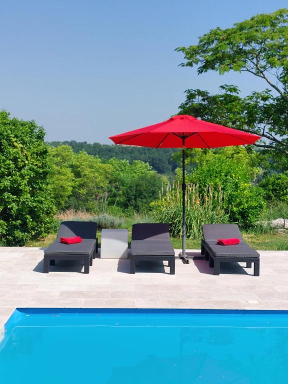 three chairs and a red umbrella next to a pool at La Maison d'Art in Lacour