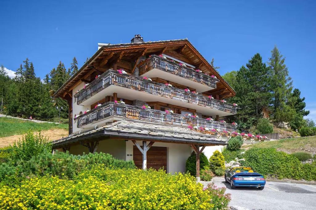 a house with balconies and a car parked in front of it at Le Cervin Rouge in Crans-Montana