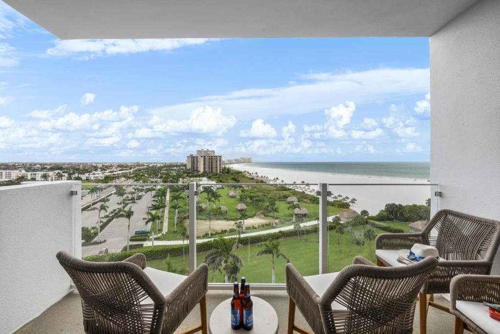 a balcony with chairs and a view of the beach at SW facing beachfront condo with sweeping ocean views in Marco Island