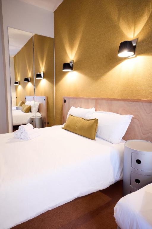 a bedroom with a large white bed and a mirror at Hôtel Henri IV in La Rochelle