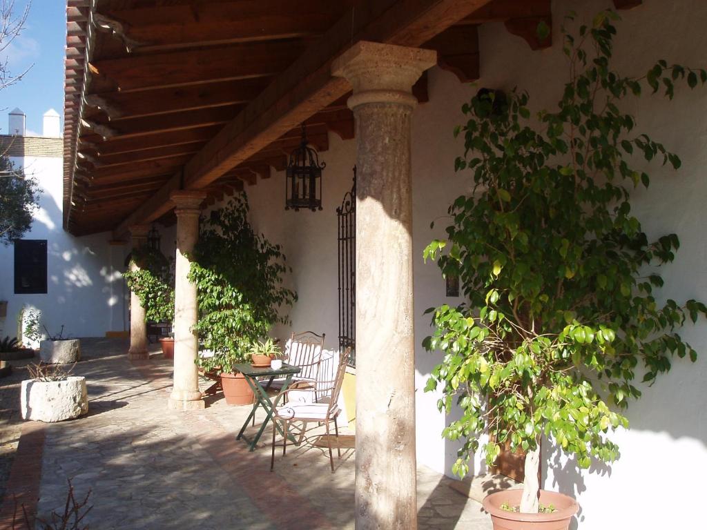 un patio con mesa y sillas bajo un techo de madera en Cortijo Los Monteros en Benalup Casas Viejas