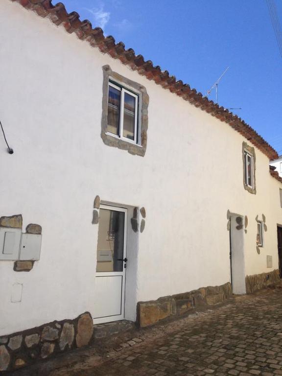 ein weißes Haus mit einer Tür und einem Fenster in der Unterkunft Thistle Cottage Alojamento Local in Gatas