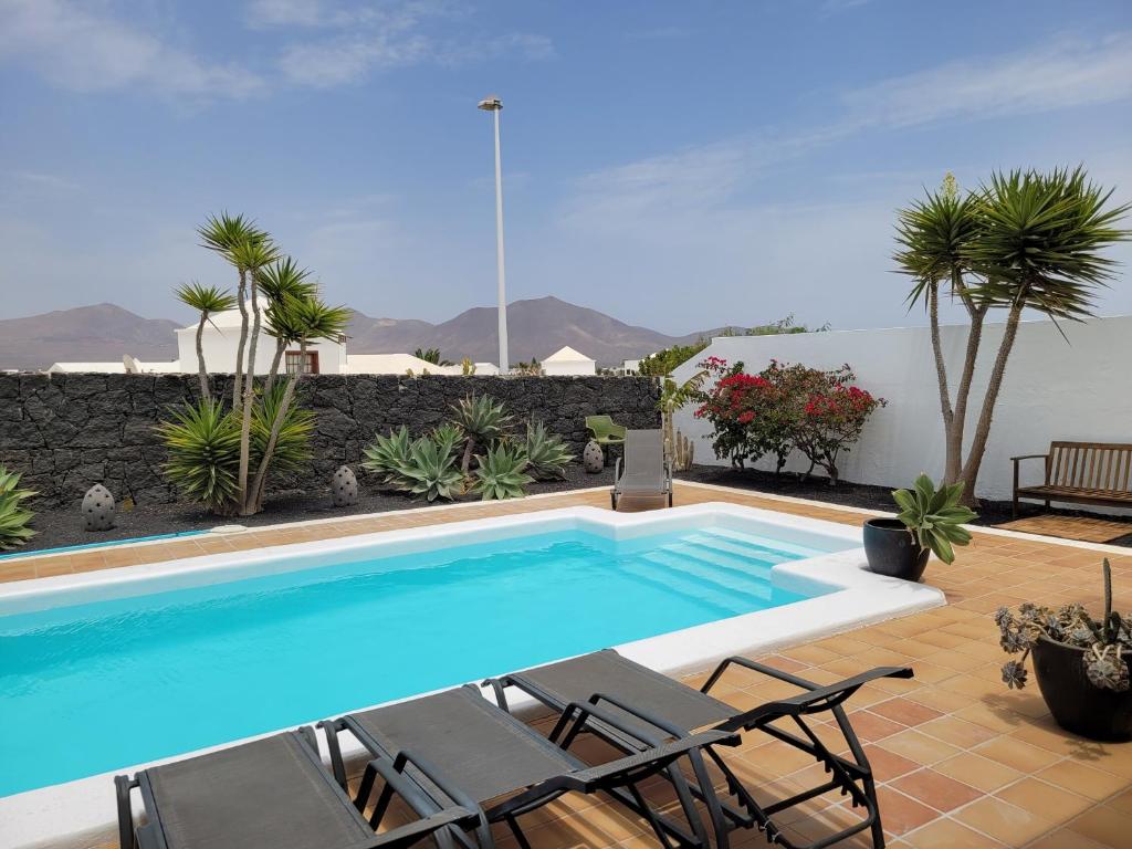 una piscina con 2 sillas de césped en Lust4Life Mirage - Luxury villa with pool, en Playa Blanca
