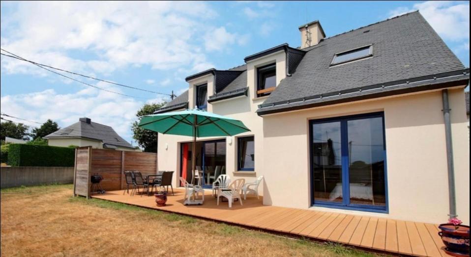 ein Haus mit einer Holzterrasse mit einem grünen Sonnenschirm in der Unterkunft La Maison Bleue in Saint-Avé