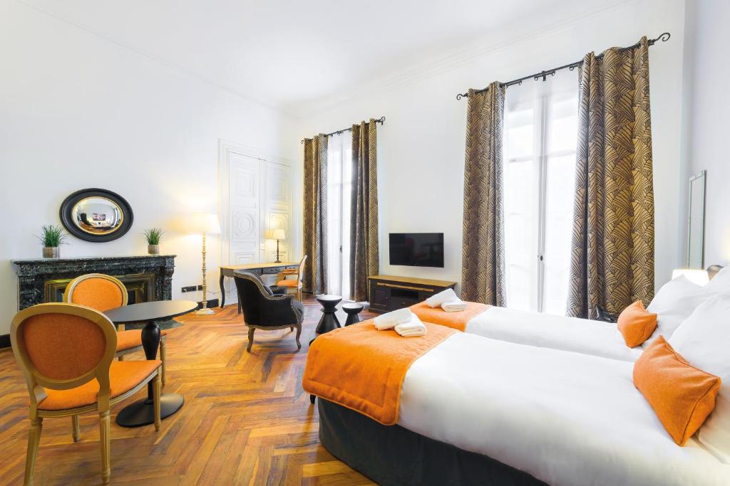 ニームにあるAppart'City Collection Nîmes Arènesのベッド、テーブル、椅子が備わるホテルルームです。